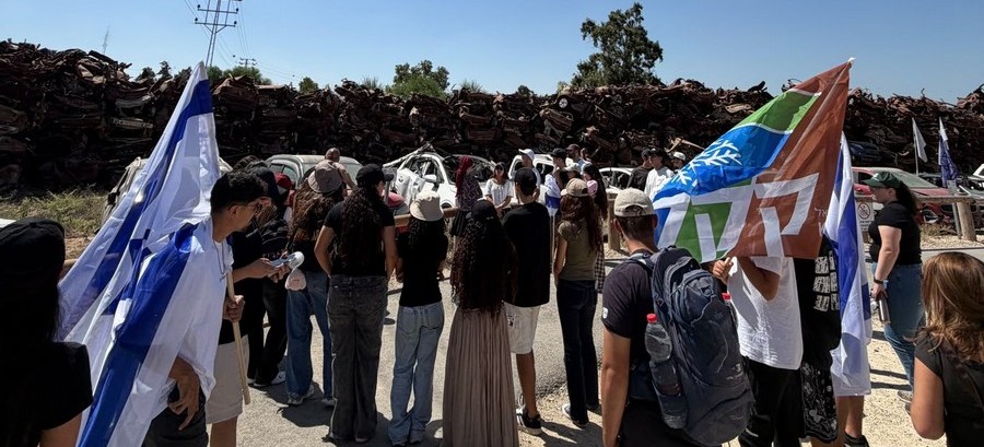 מתבוננים בקיר המכוניות השרופות. צילום: מדריכי בית קקל בעכו. ארכיון הצילומים של קקל 