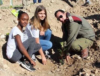 חייל ושלוש ילדיות נוטעים ביחד