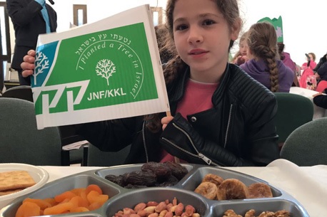ילדה עם דגל קק"ל ופירות יבשים בסדר החגיגי.  צילום: אורנית גינת