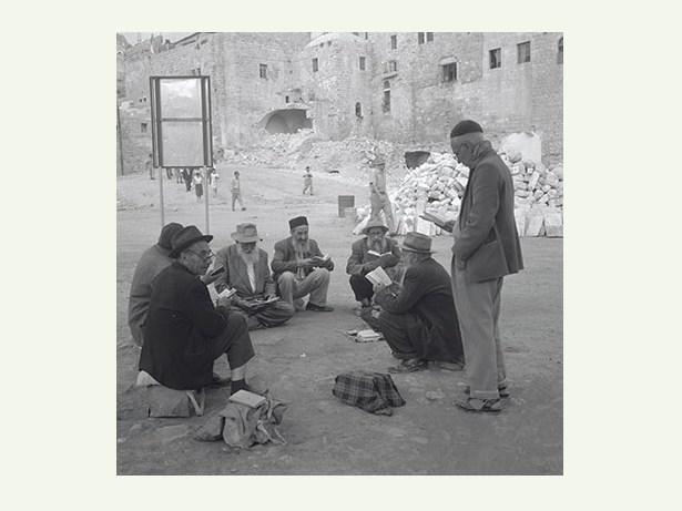 לקונן או לשמוח? 1967 / קבוצת מתפללים, כנראה בימי בין המְצָרִים, מתאבלת על חורבן הבית, ליד הכותל המערבי / צילום: דוד הירשפלד, ארכיון הצילומים של קק"ל
